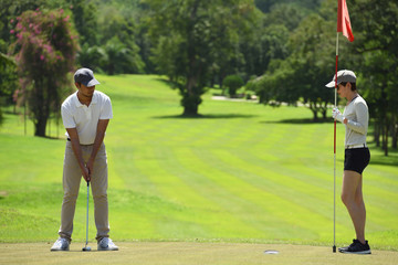 Obraz premium Man and woman playing golf on a beautiful natural golf course