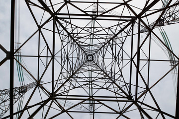 Power industry. Construct of a tall metal tower of high voltage electrical line against the sky. Bottom up view
