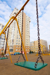 Swings on chains in the yard of multi storey block of flats