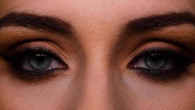 Close up shot of a beautiful woman opening and closing her blue eyes. Make-up.