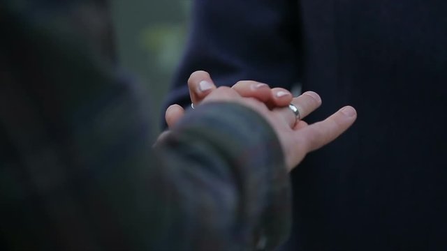 Bride wears ring on groom's finger. Marriage hands with rings. Wedding day.