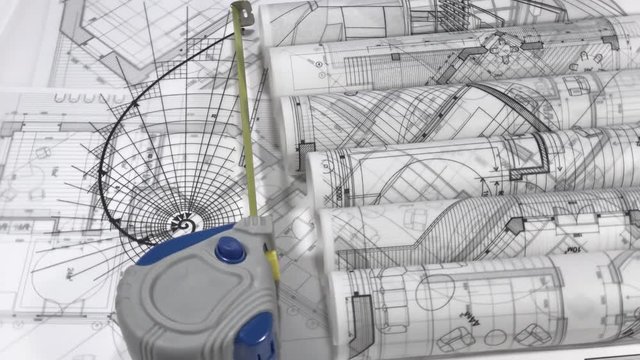 Blueprints - rolls of architectural drawings, roulette and drawing of the golden section on the surface of the architectural plan of a modern house