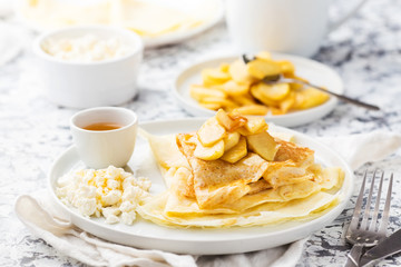 Traditional thin pancakes with apple, cottage cheese  and honey on a white plate. Healthy breakfast