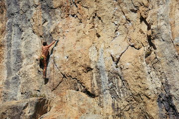 Young man climbs the yellow rock, hard route 7c, lead.