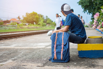 Man backpacker waiting train at train station for traveling with vintage tone. subject is blurred and noise.