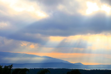 Ray of beautiful sun light shines through the cloud over the mountain