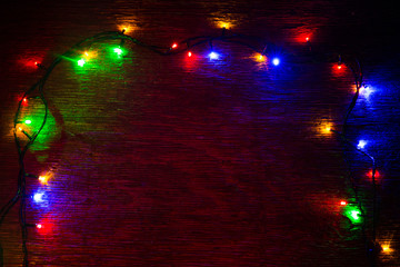 multicolored Christmas lights on a wooden background