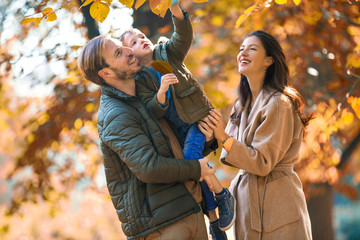 Young family having fun in the autumn park with his son.