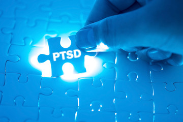 Doctor hand holding a jigsaw puzzle with PTSD - post traumatic stress disorder. War veteran mental...