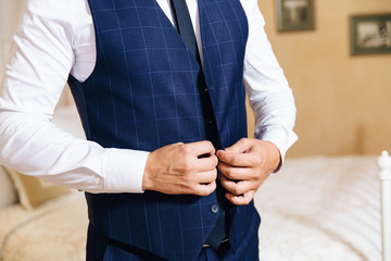 Close-up of a cropped frame of a business stylish man buttoning his jacket, standing in a stylish office with designer repair.