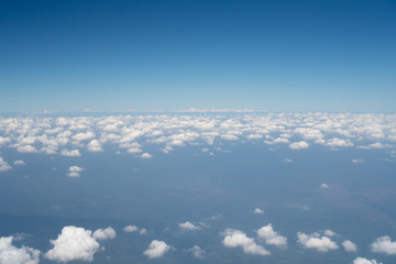 Blue sky view above the white mostly cloudy from the airplane window