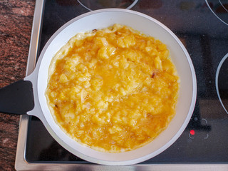 Mix of potatoes, onion and eggs yolks on white pan frying in oven. Spanish omelet recipe