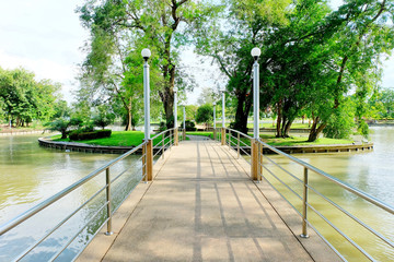 Concrete bridges with electric pole. Bridges over the river to the public park. Small island in the middle of the pond with sunlight.