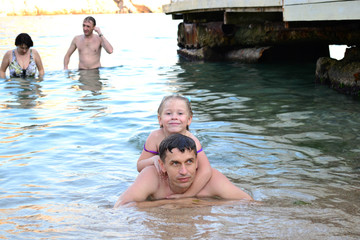 a man with a child happily swim in the sea  