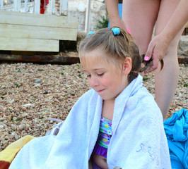 girl sitting wrapped in a towel after bathing on the beach  