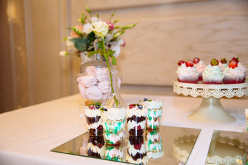 Candy bar, a table with sweets and desserts on the table. Buffet with delicious cupcakes, cake pops, biscuits, flowers.