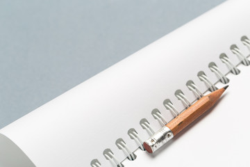 Short worn pencil with notepad on gray desk