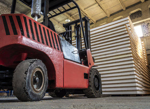Orange forklift working on a warehouse of construction panels.