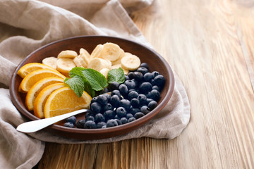 Plate with delicious fruit salad on wooden table