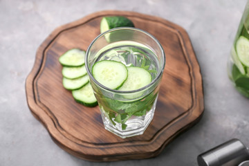Glass with tasty fresh cucumber water on wooden board