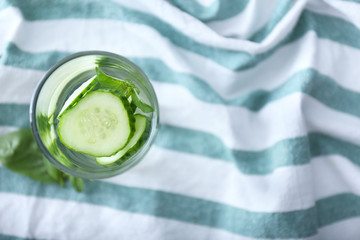 Glass with tasty fresh cucumber water on napkin