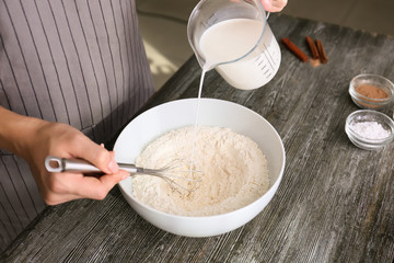Woman making dough for preparing of delicious waffles at wooden table