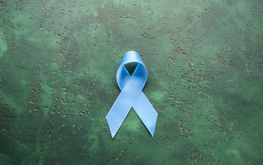 Blue ribbon on color background. Cancer concept