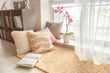 Cozy place for rest with soft pillows and book near window