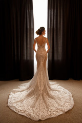 Wedding. Beautiful bride in luxury wedding dress posing near window