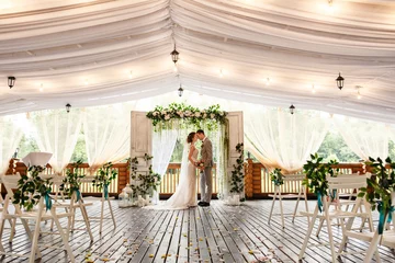Foto op Plexiglas Wedding ceremony. Elegant wedding couple kissing near wedding arch, bride and groom in love © Wedding photography