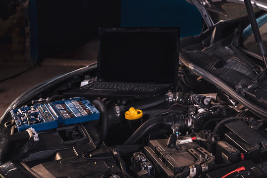 Car service worker diagnoses car breakdown.