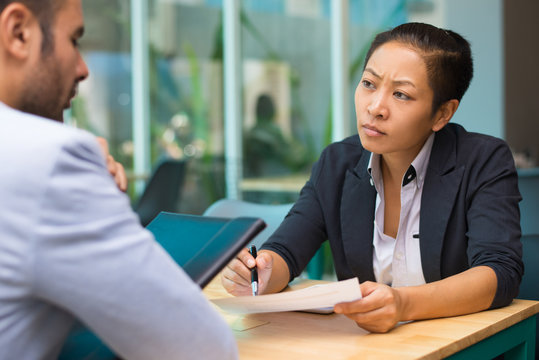 Serious Asian executive manager meeting with job applicant in modern conference room. Multiethnic colleagues discussing marketing project. Job interview or teamwork concept