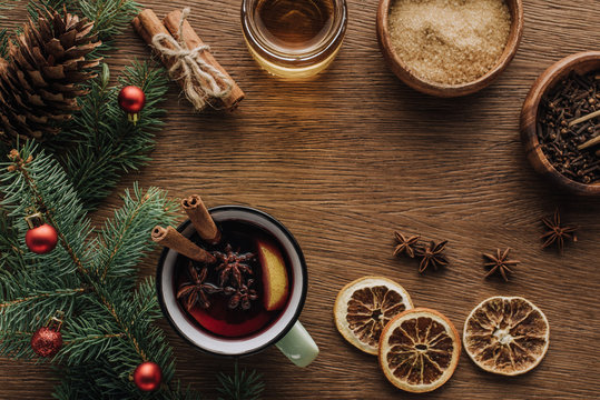 top view of spice mulled wine and fir twigs with baubles on wooden tabletop, christmas concept