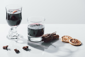 mulled wine in glasses and cinnamon sticks on white tabletop