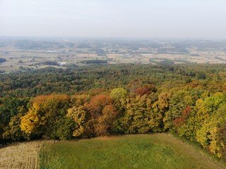 abgeerntetes Feld und verfärbte Wälder im Herbst