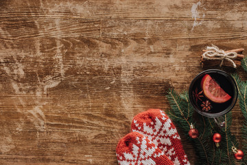 top view of cup of mulled wine, fir twigs and mittens on wooden tabletop, christmas concept