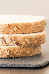 Slices of homemade multigrain bread on black slate board