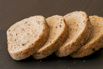 Slices of homemade multigrain bread on black slate board