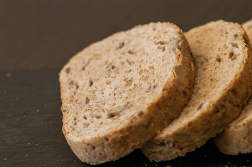 Slices of homemade multigrain bread on black slate board