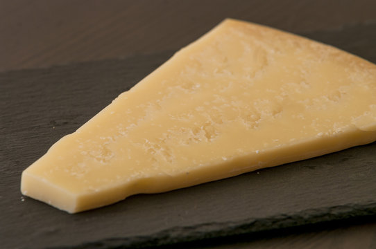 Slice of cheese on black slate board, close-up