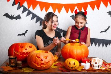Fototapeta premium Happy Halloween! Mother and daughter carving pumpkin. Family preparing for holiday.
