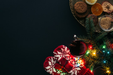 top view of cup of mulled wine, garland, mittens and cookies isolated on black, christmas concept