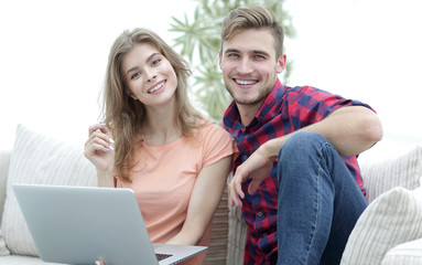 young couple of students with laptop sitting on the couch