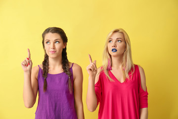 Portrait of beautiful women with raised index fingers on color background