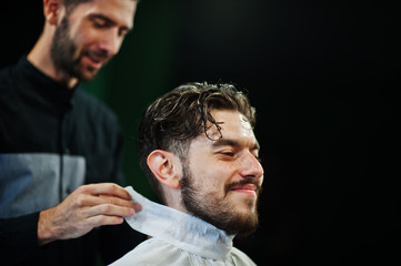 Handsome bearded man at the barbershop, barber at work.