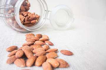 Almonds spread from the jar on the top of table.
