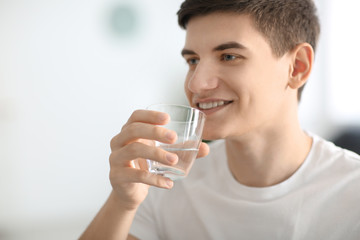 Young man drinking water at home