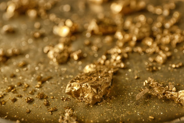 Gold nuggets on metal surface, closeup