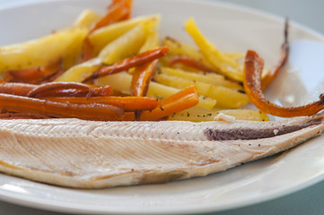 Tasty baked fish with fried fries and carrot slices on plate