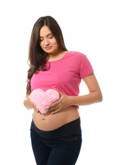Beautiful pregnant woman with plush heart on white background